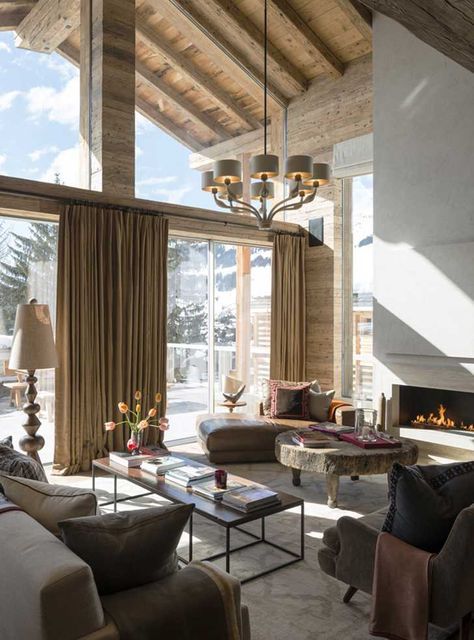 a light-filled chalet living room with a neutral fireplace, leather seating furniture, a coffee table of wood and metal and neutral textiles
