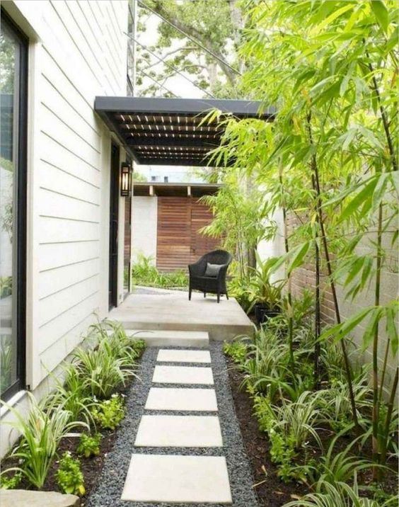 un patio delantero de bajo mantenimiento con guijarros, tejas, vegetación y bambú es una hermosa idea para una casa moderna