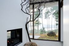 a mini Japanese courtyard with moss, a large rock and a single tree plus a built-in fireplace and a skylight