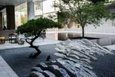 a minimalist Japanese courtyard with a rock that seems to be sliced, two low trees and a sleek pond around one of them