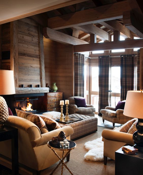 a modern cozy chalet living room with stained walls, a fireplace, plaid seating furniture, a side table and candles plus plaid curtains