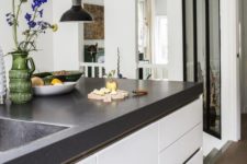 a modern white kitchen with a large kitchen island with a black concrete countertop is veyr welcoming