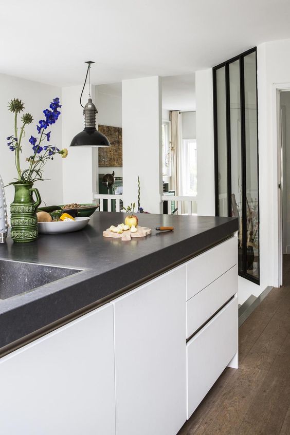 a modern white kitchen with a large kitchen island with a black concrete countertop is veyr welcoming