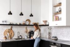 a monochromatic kitchen with black cabinets, a concrete countertop and a grey tile backsplash