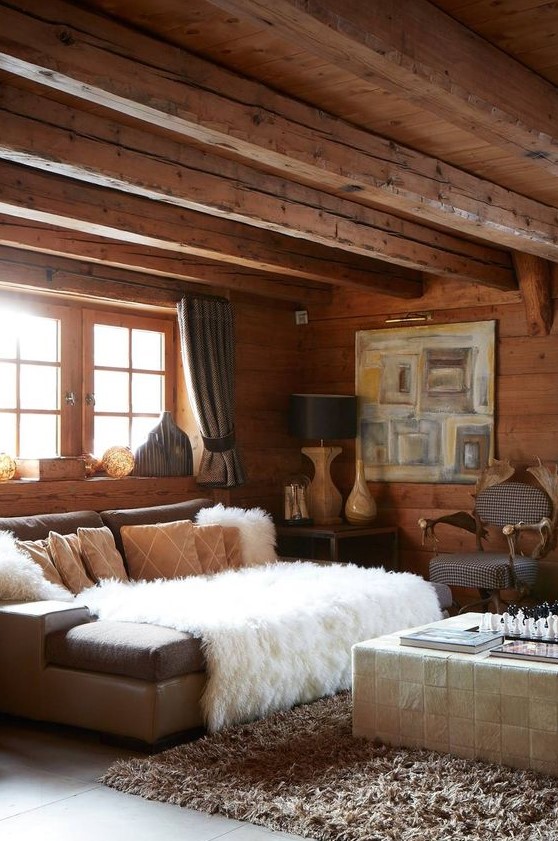 a refined chalet living room with walls, a ceiling and a floor of wood, neutral furniture and vintage lamps
