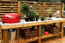 a relaxed rustic bbq zone of wood and concrete, with many potted herbs and a grill plus open storage space