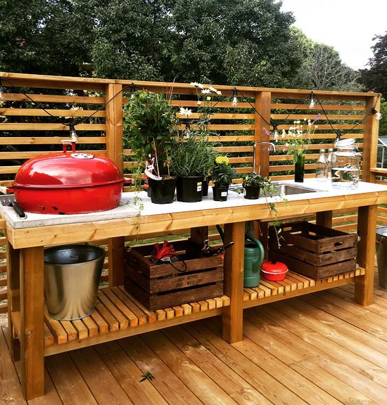 a relaxed rustic bbq zone of wood and concrete, with many potted herbs and a grill plus open storage space