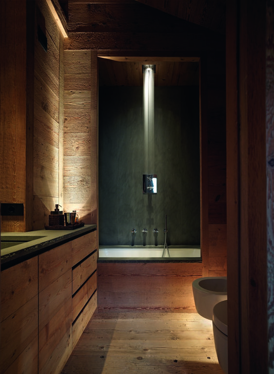 a relaxing chalet bathroom clad with wood, with a rainshower and a bathtub, a built-in vanity and built-in lights