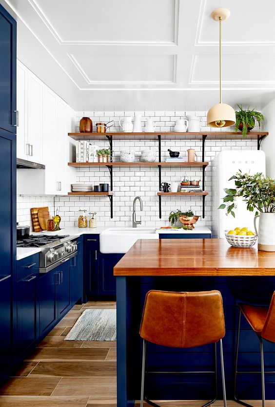 a rich stained wooden countertop and leather stools that highlight it make this bold blue kitchen brighter