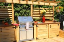 a rustic outdoor bbq area of light stained wood, with much cooking space and a large grill