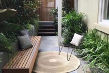 a small townhouse garden with stone tiles, a built-in bench, hairpin leg furniture and potted greenery with much texture