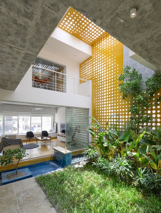 a small yet cozy inner courtyard with lots of greenery and grass lit through perforated panels above