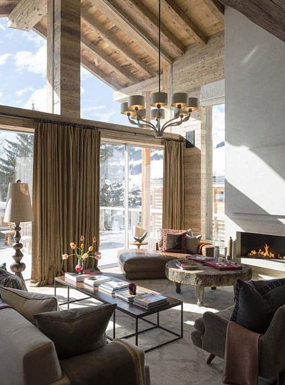 a sophisticated chalet living room in neutrals, with a fireplace, stylish furniture, a round table and a glazed wall