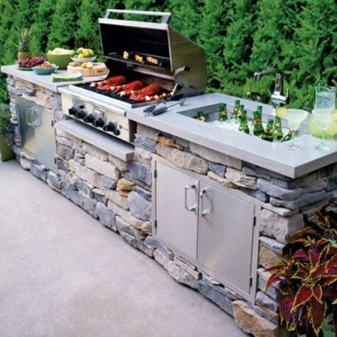 a traditional outdoor bbq area with a stone unit, a concrete countertop, a grill, a cooking zone and a drink cooler