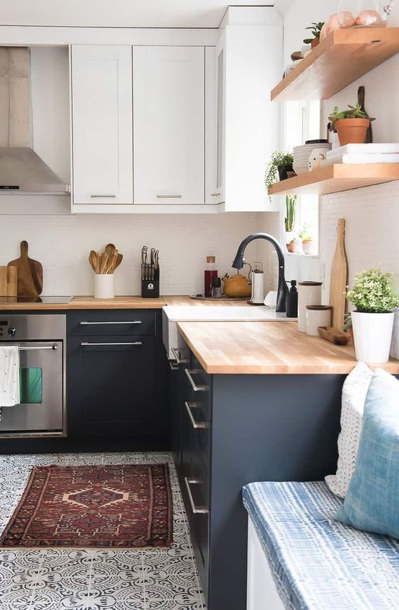 a trendy two tone kitchen in black and white and with light stained butcherblock countertops and matte black faucets