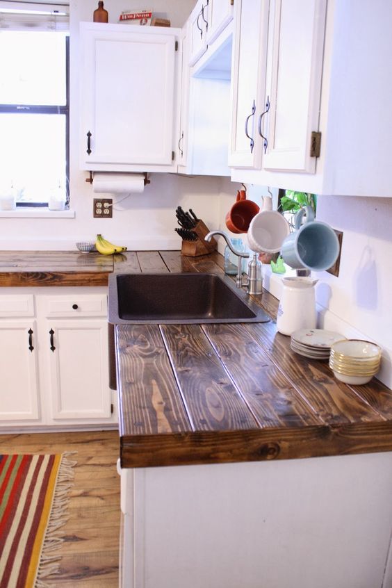 a vintage white kitchen with rich stained wooden countertops and black handles is a stylish space with a contrast