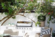 a welcoming outdoor bbq area with a grill and some cooking space plus a dining zone with wicker furniture