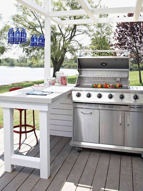 a welcoming outdoor bbq area with a large grill, an eating space by its side and blue bottles over it