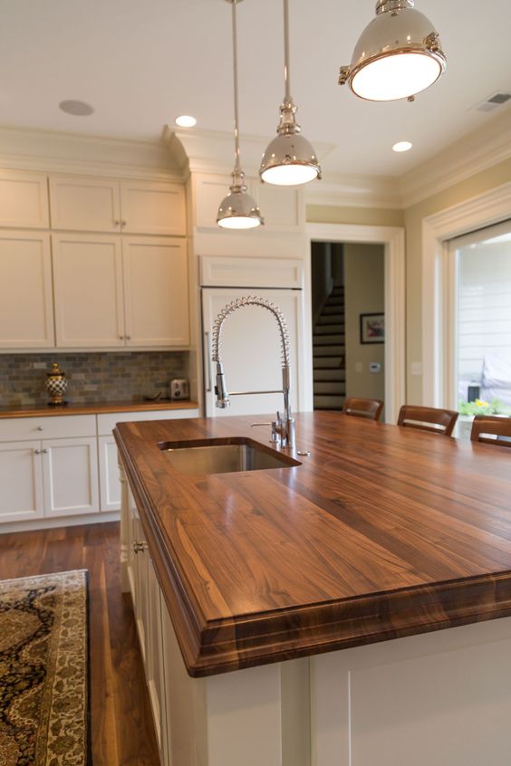 a white farmhouse kitchen with rich stained wooden countertops that add warmth and chic to the space