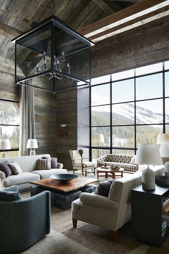 an elegant chalet living room with reclaimed wooden walls and a ceiling, neutral furniture and a large glass chandelier