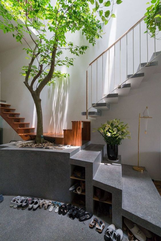 an indoor courtyard and an entryway in one, with a real tree growing in a cinder block pot and skylights over the space