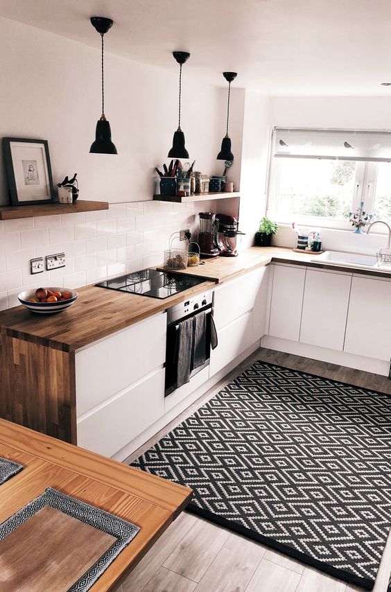 an ultra-modern white kitchen with butcherblock countertops and a printed rug looks bold and cool