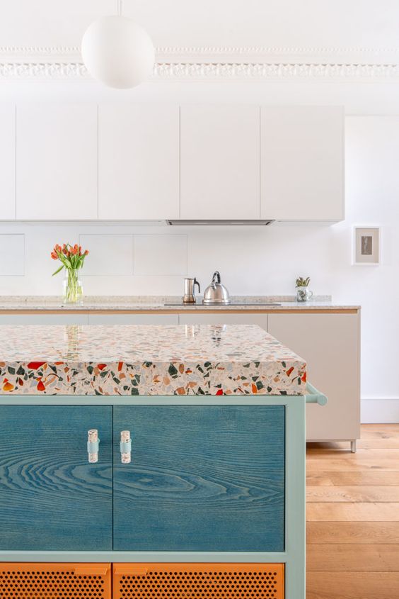 colorful terrazzo countertops spruce up the neutral kitchen and add catchiness to the bold blue island