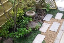 grass, concrete tiles, shrubs, a thin tree, a stoen bowl fountain and rocks for a lovely and chic Japanese-inspired look