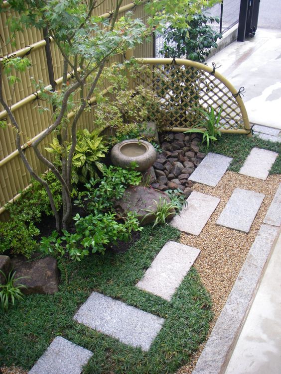 césped, tejas de concreto, arbustos, un árbol delgado, una fuente de piedra y rocas para una apariencia hermosa y elegante de inspiración japonesa.