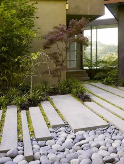 pebbles, long and narrow tiles, grass and mini Japanese trees at the entrance make the front yard very elegant, sleek and catchy