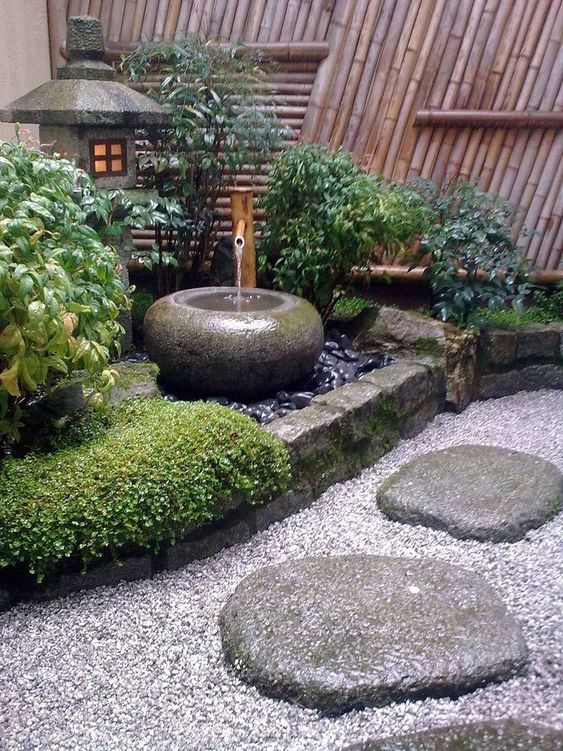 guijarros, rocas, hierba, arbustos, una fuente de piedra y una linterna de piedra para un hermoso y elegante jardín japonés