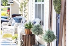 simple porch decor with white wicker chairs, potted greenery and a crate as a side table
