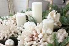 a Christmas centerpiece of a bread bowl, evergreens, corals, ornaments, candles and greenery is a lovely idea for a coastal space