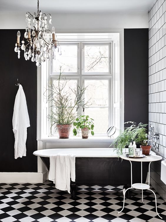  افكار ديكورات حمام فينتج انيقة وفخمة  A-black-and-white-vintage-bathroom-with-white-square-tiles-a-black-and-white-floor-a-black-statement-wall-a-crystal-chandelier-and-lots-of-greenery