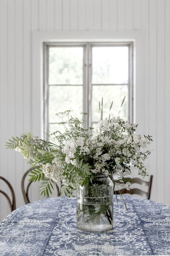 a clear vase with fresh white blooms and some leaves is a nice summer centerpiece or decoration