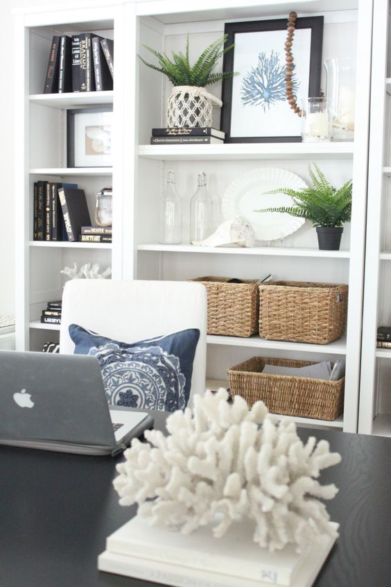 a coastal home office with a coral artwork and a coral on a stand plus greenery in pots is a very cool idea for a beachy space