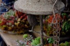 a concrete lantern with succulents and greenery and some chains for outdoor decor