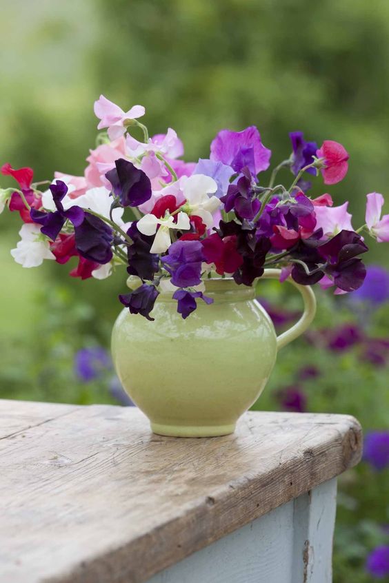 a green milkpot with bright florals is a nice rustic-style centerpiece or decoration for your summer space