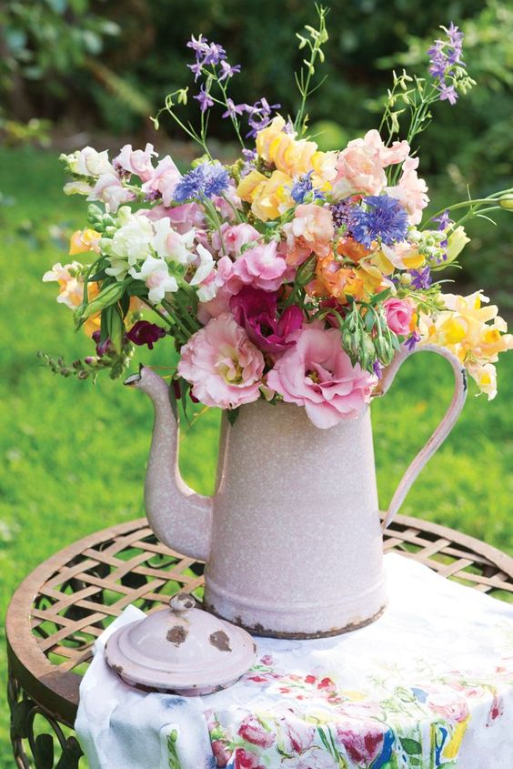 a light pink teapot with a colorful floral arrangement is a bright and cool decoration with a vintage feel