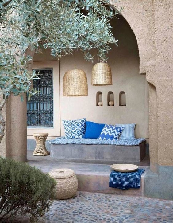 a lively Mediterranean patio with a built-in bench, blue upholstery, wicker pendant lamps, a side table and niches for storage