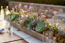a long wooden planter with lots of succulents and some pink blooms is a chic and bold rustic centerpiece to rock