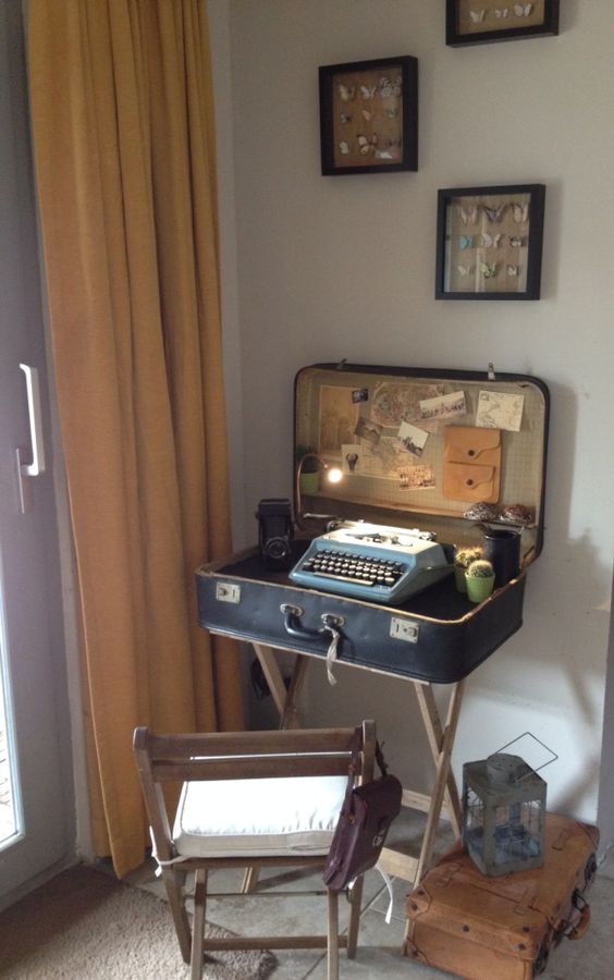 a mini desk made of a vintage suitcase, with a typewriter inside, some lights, cacti and a vintage camera and potos for decor