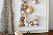 a monogram seashell artwork and some corals and seashells on fishing net for coastal and beachy decor