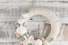 a pretty rope wreath with starfish, seashells and various pearls looks very coastal or beachy