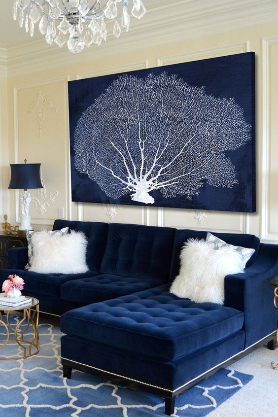 a refined nautical living room with a navy sofa and a dried coral artwork, refined lamps and a rug is amazing