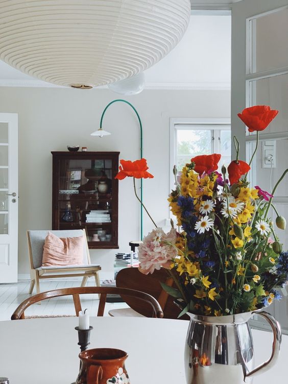 a silver milkpot with colorful blooms is a bright and fun decoration or centerpiece with a relaxed feel