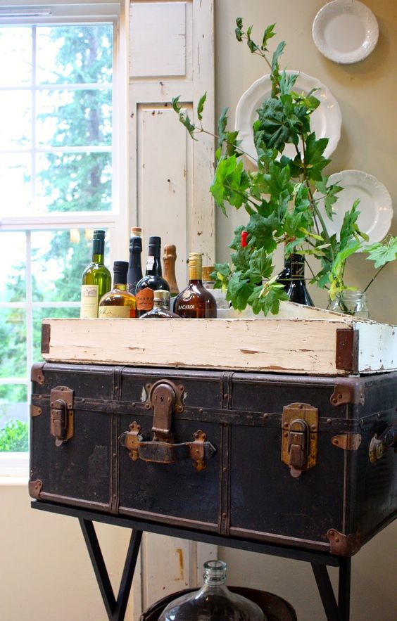 a sophisticated home bar composed of a black suitcase and a tray with various alcohol on top is a smart and chic idea