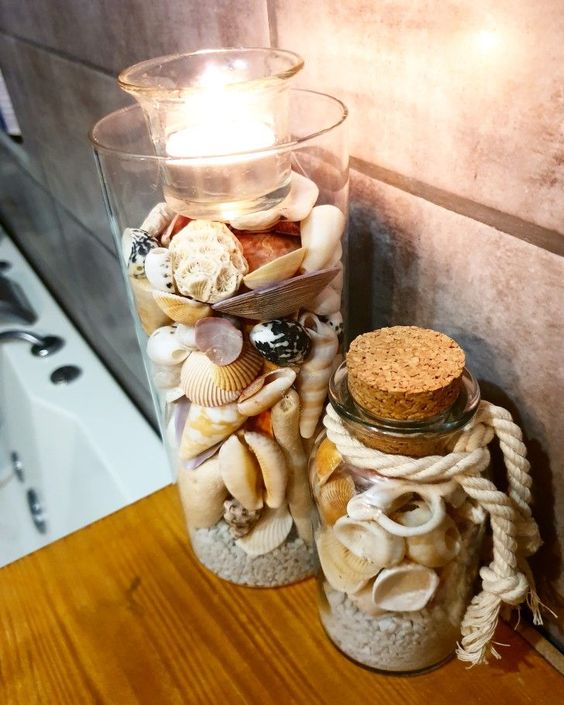a tall vase and a bottle with beach sand and seashells plus a candle on top are a nice decoration or centerpiece