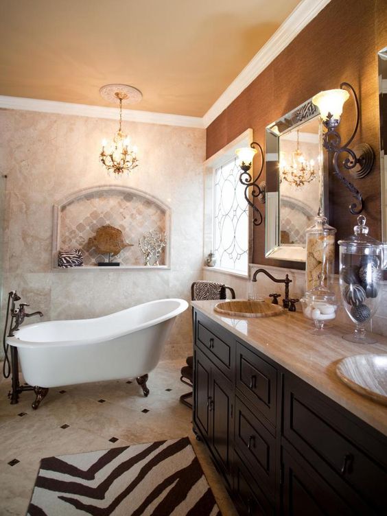 a vintage bathroom with marble and neutral tiles, a taupe wall, a dark-stained vanity, a clawfoot bathtub and vintage lamps