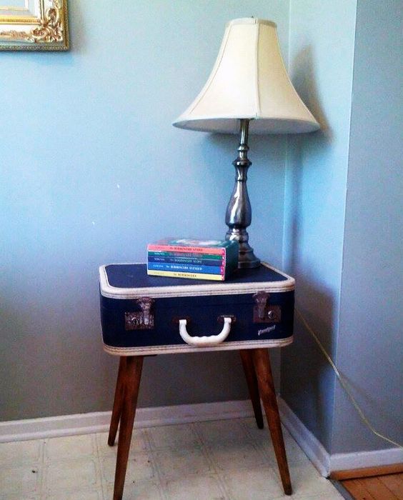 a vintage suitcase on stained legs as a coffee table with books and a table lamp is a bold and cool idea for a vintage-infused space